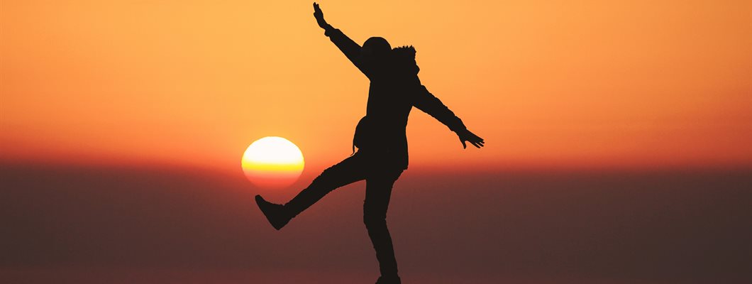 Silhouette of a person standing on a rock with a sunset background 