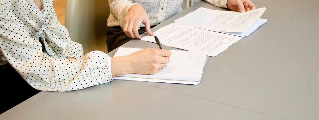 Two women sat at a desk going over paperwork