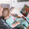 Photo by Piscea on Unsplash of a dad with a baby on lap looking at a children's story book together.